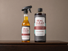 Two bottles of 'Real Clean Floors' cleaning products on a wooden surface with a neutral background.