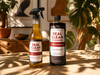 Two bottles of 'Real Clean Floors' products on a wooden surface with plants in the background.